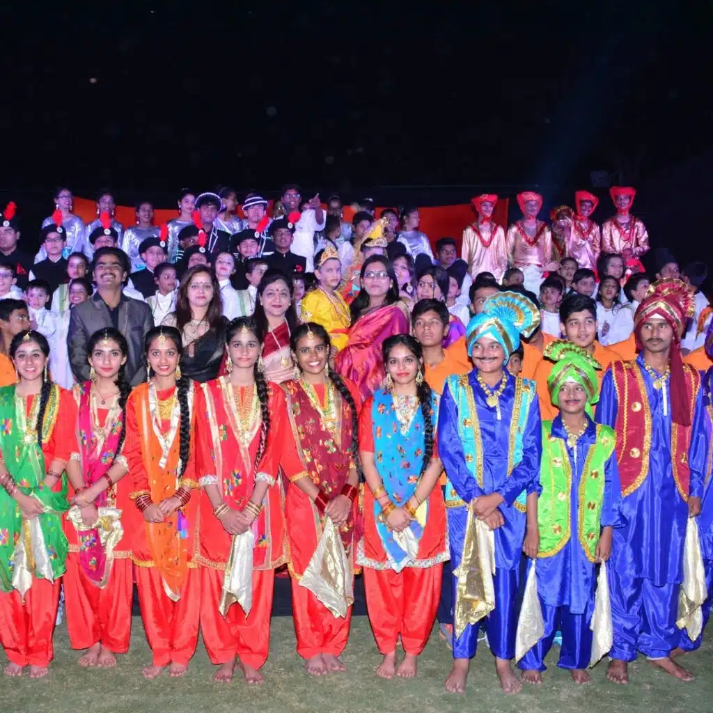 Group of children dressed in colorful traditional Indian costumes posing together during a cultural performance or school event.